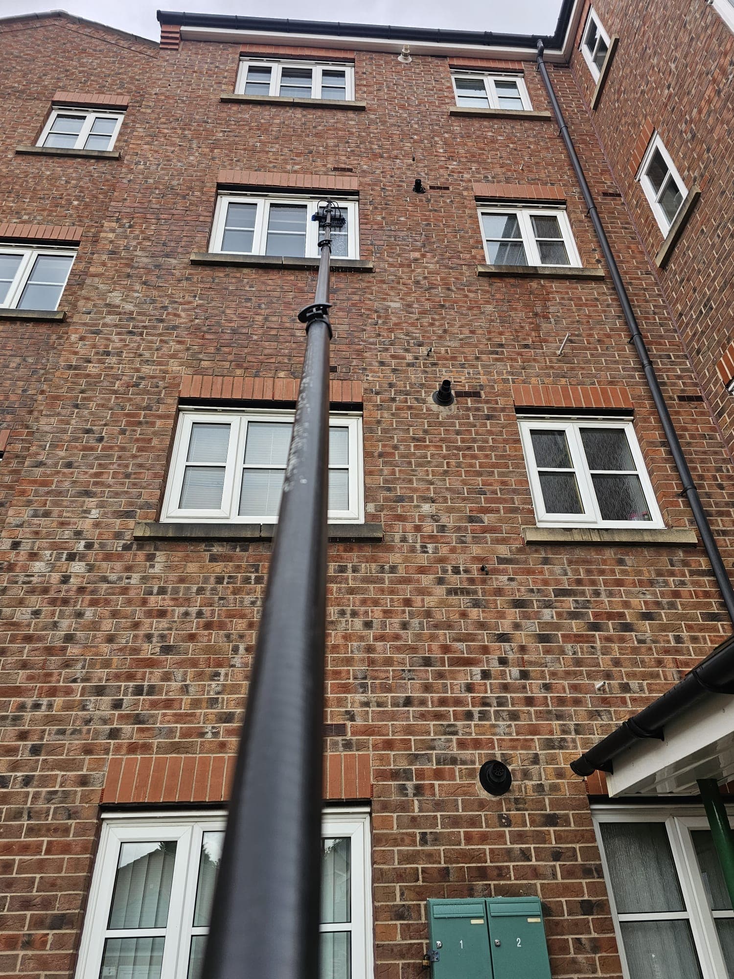 Commercial window cleaning in Barnsley - water-fed pole reaching upper-floor windows of an apartment block